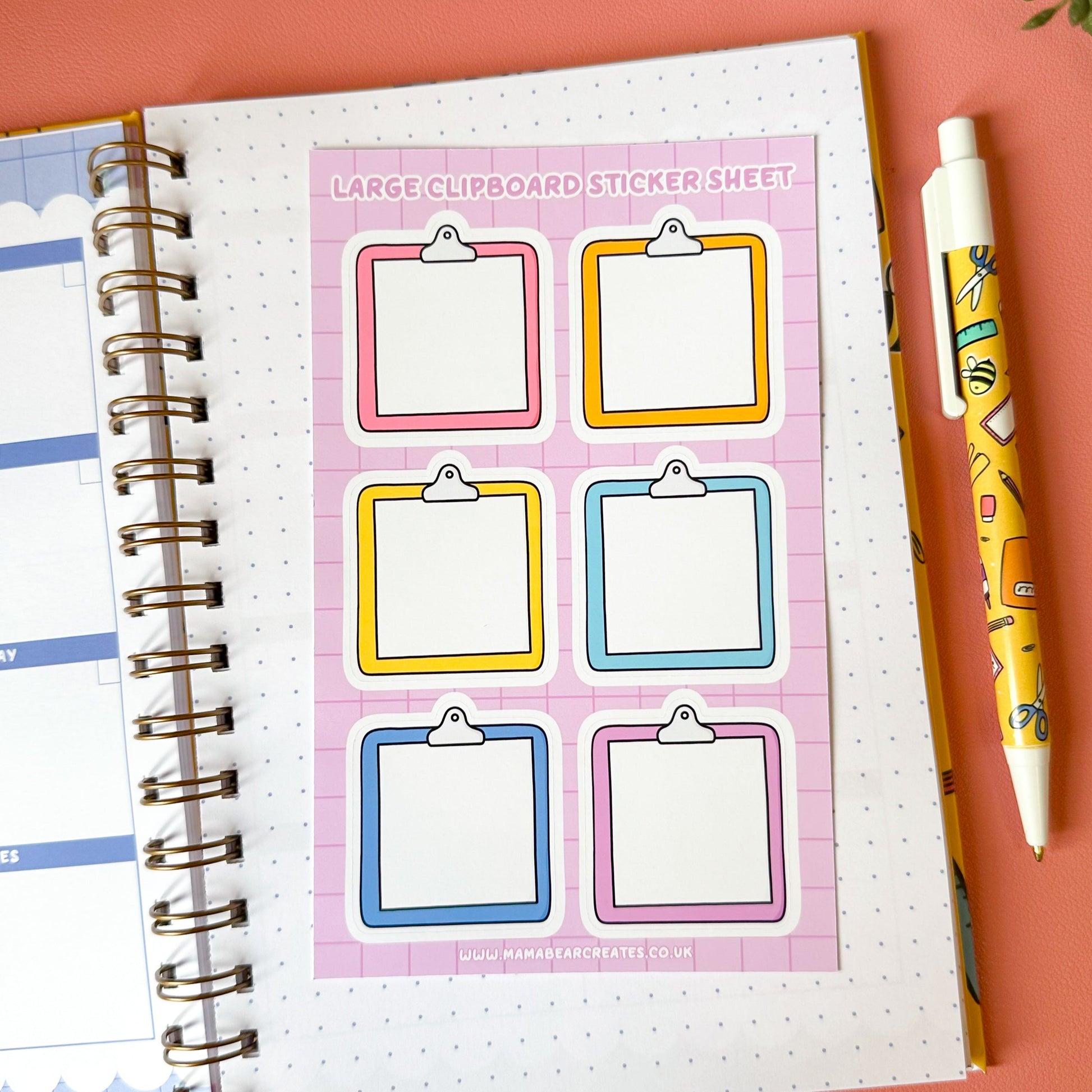 Sheet of large clipboard stickers on a notebook with a pen and plant on a pink background