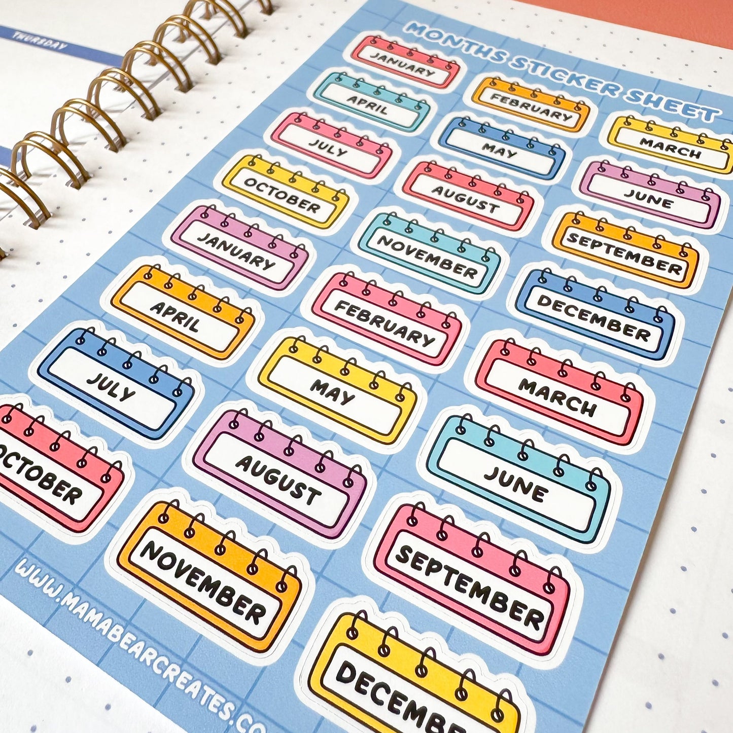 Sheet of colorful month labels on a planner with 'Mama Bear Creates' branding.