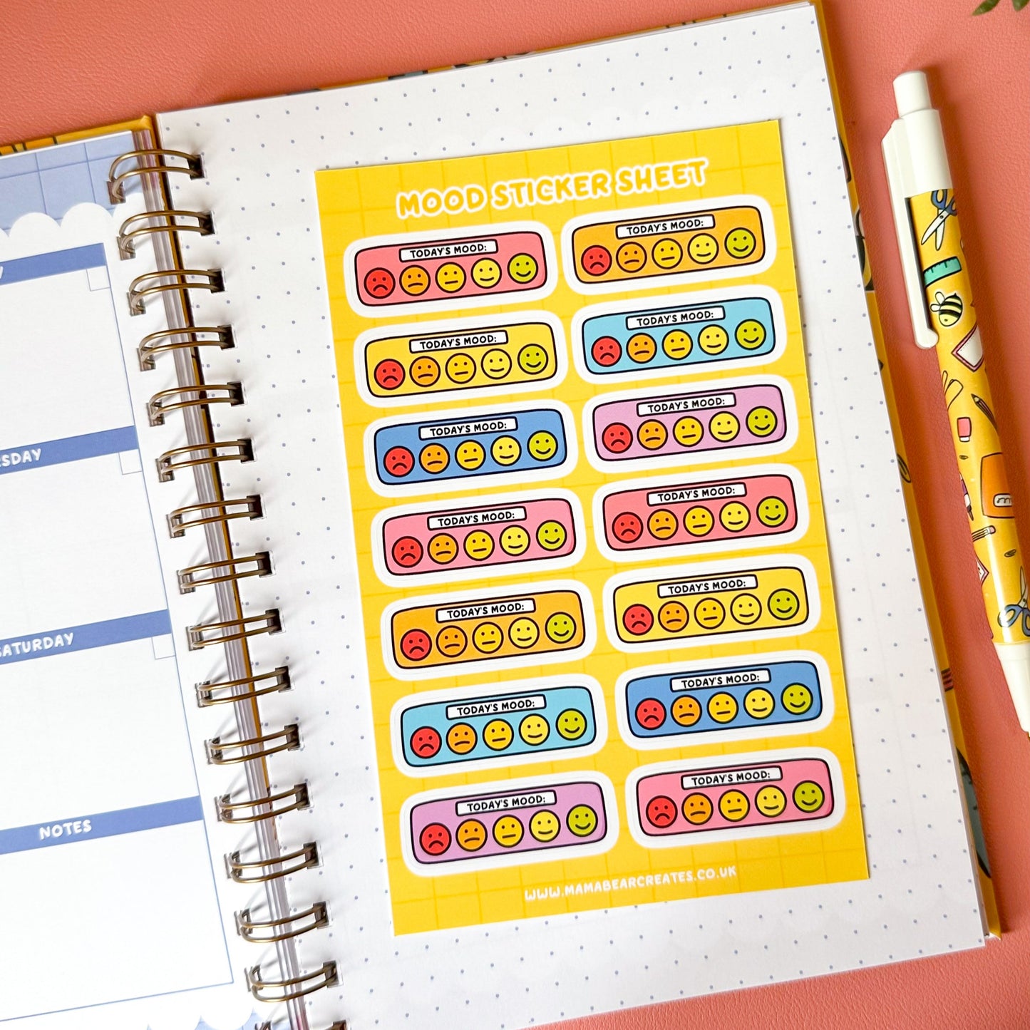 Sticker sheet with colorful labels on a planner page with a pen and plant in the background.