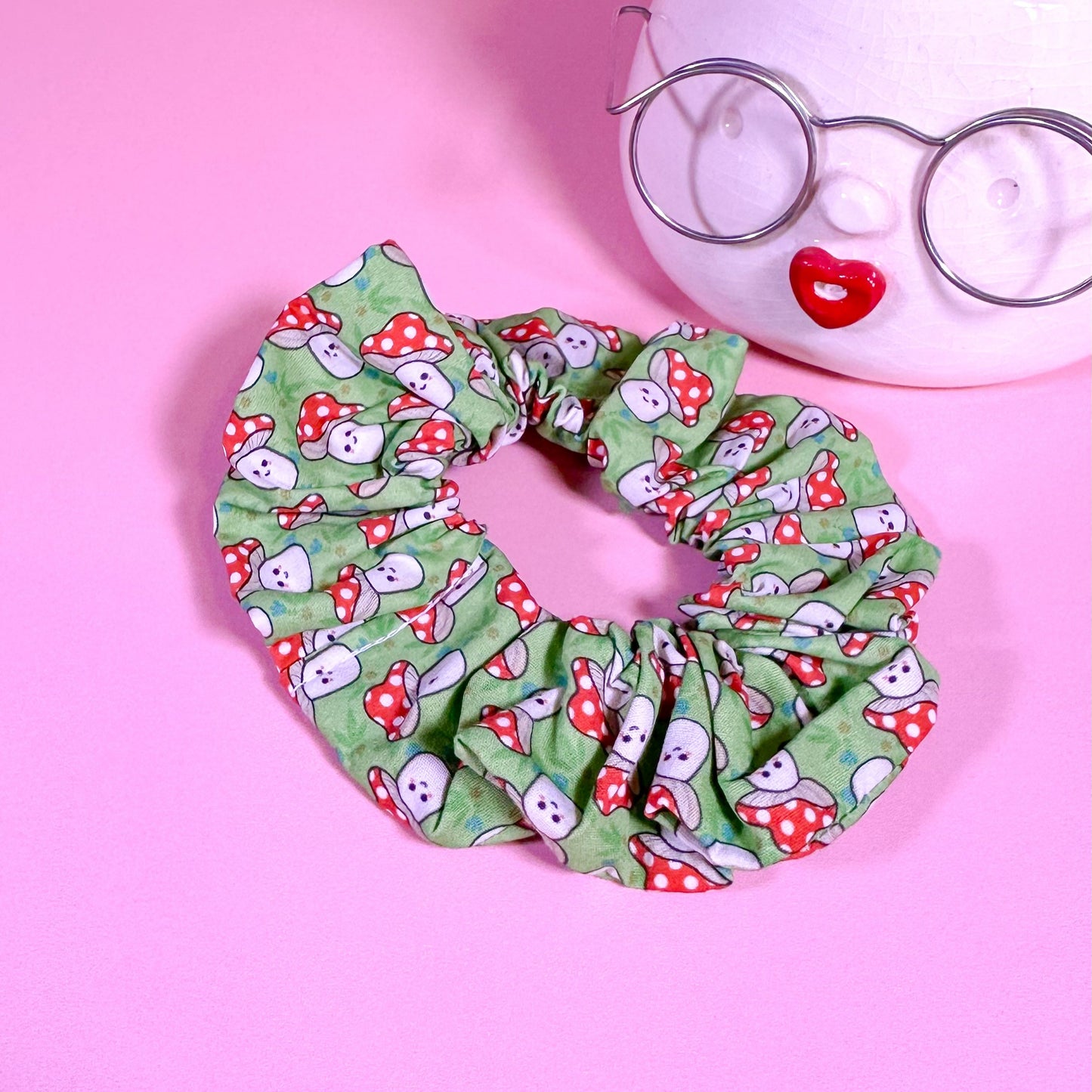 Green scrunchie with cartoon pattern on a pink background