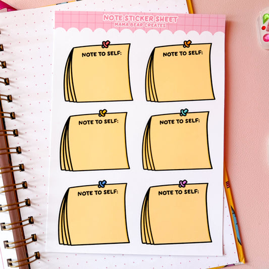 Sheet of 'Note to Self' stickers on a notebook with stationery items on a pink background