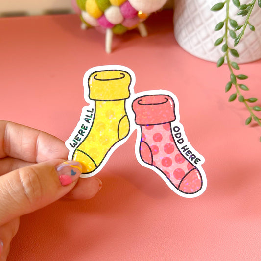 Hand holding a sticker with yellow and pink socks on a pink background