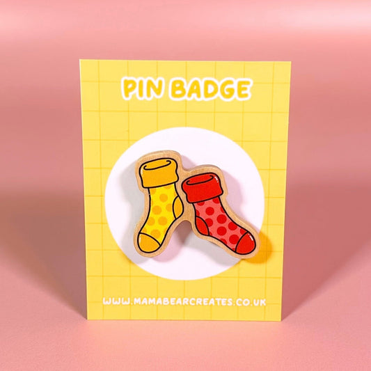 Pin badge packaging with two socks on a yellow background