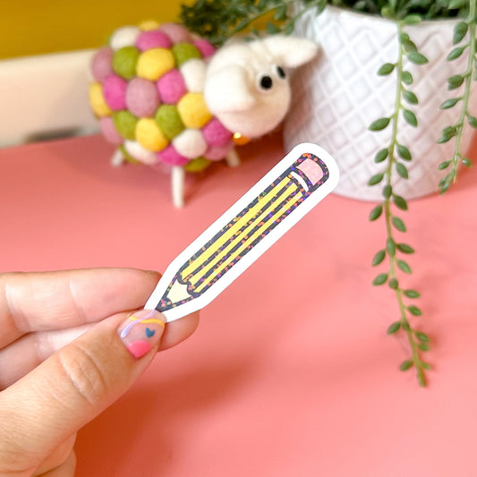 Hand holding a pencil sticker with a pink background and decorative elements.