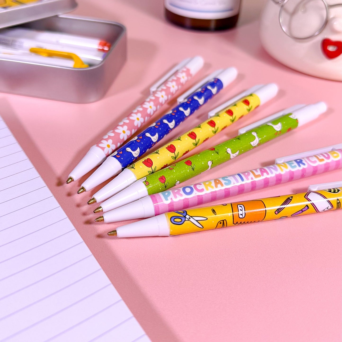 Colorful pens with cartoon designs on a pink surface