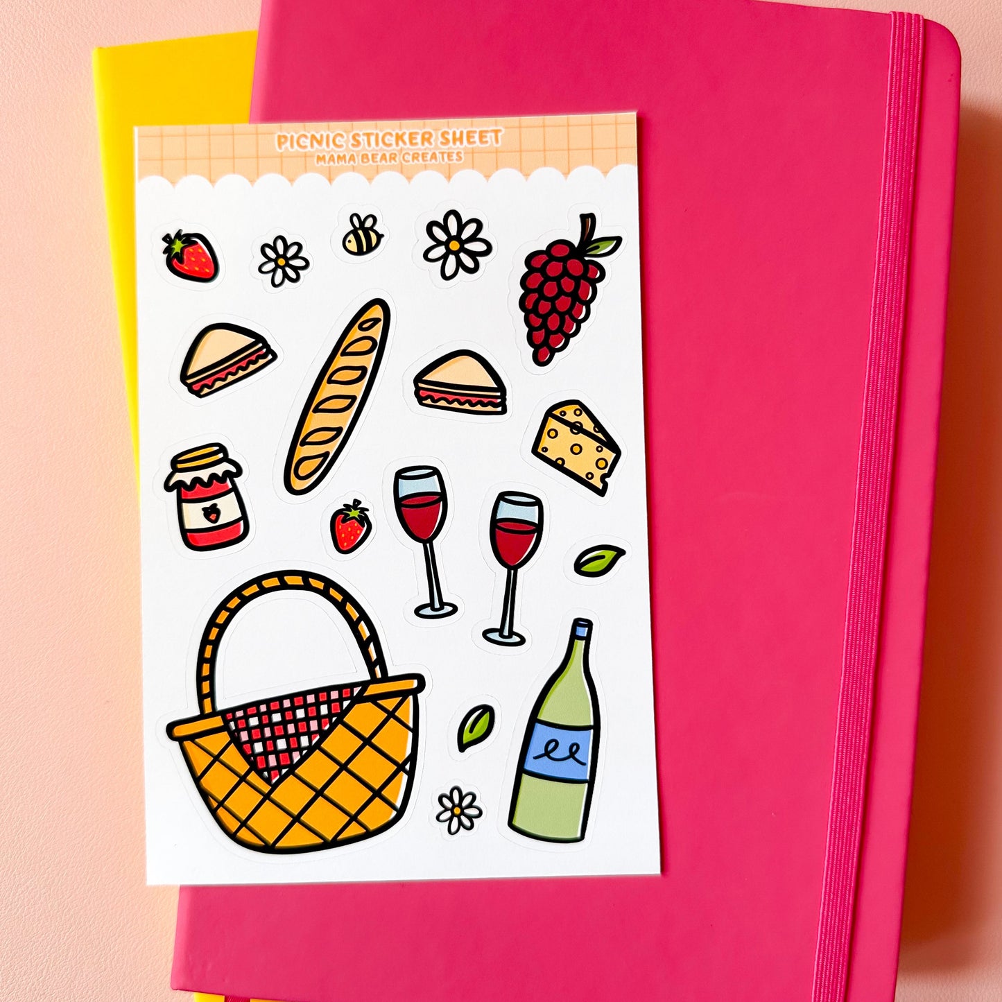 Pink notebook with a sticker sheet featuring picnic-themed illustrations on a pink background