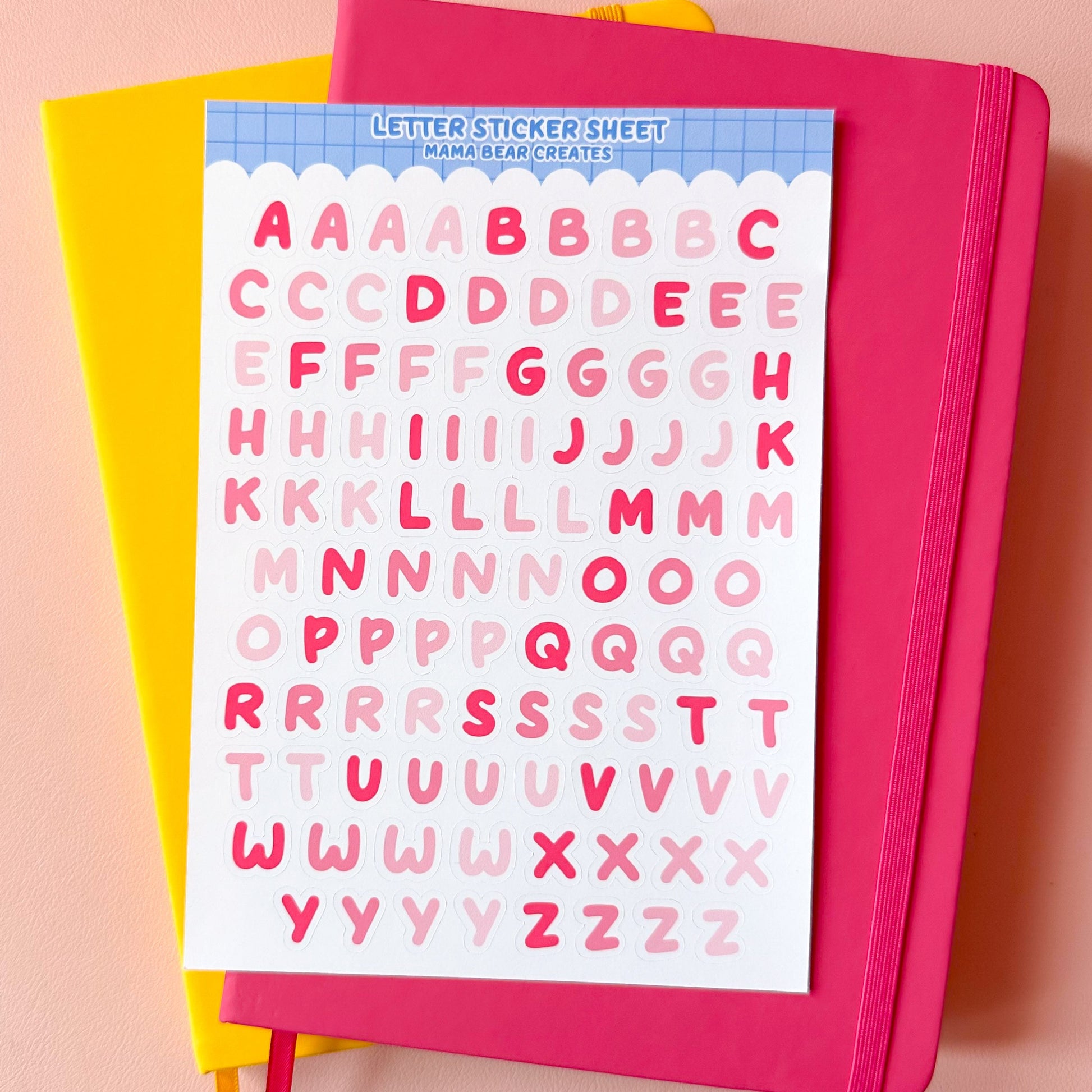 Pink notebook with letter sticker sheet on a pink background