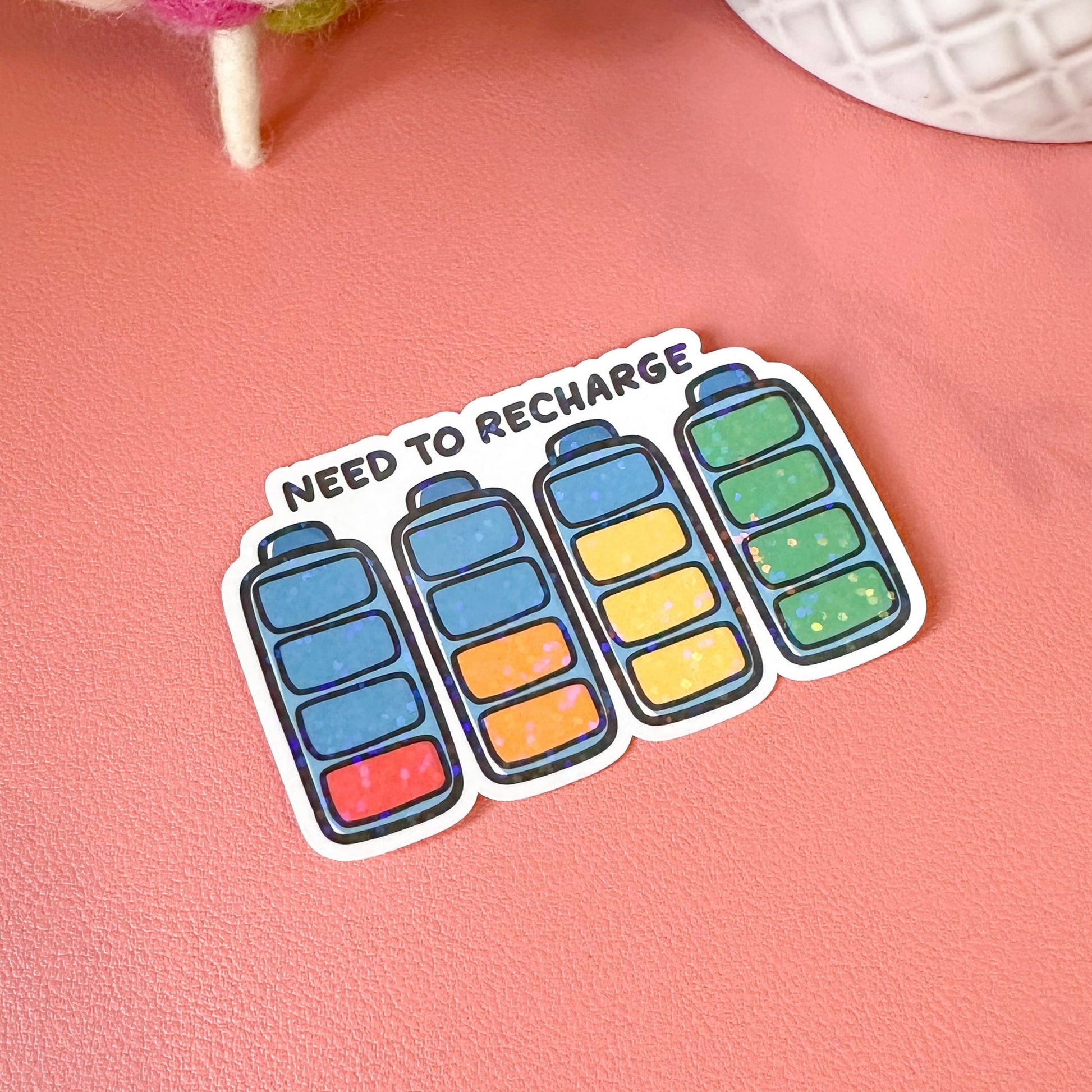 Sticker with colorful battery icons and 'Need to Recharge' text on a pink background