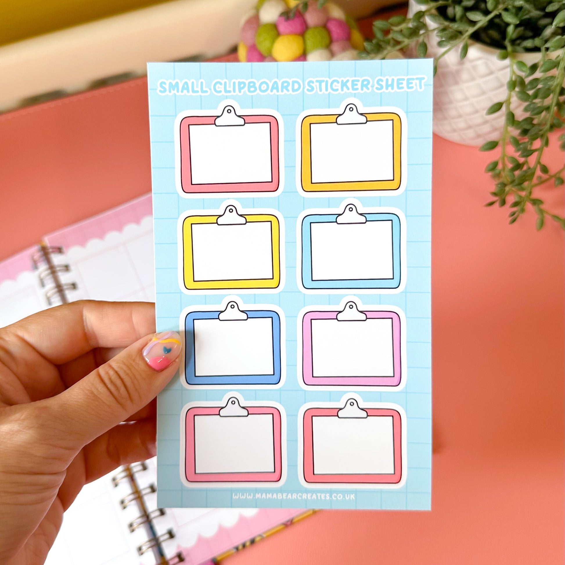 Sheet of small clipboard stickers held by a hand with a colorful background