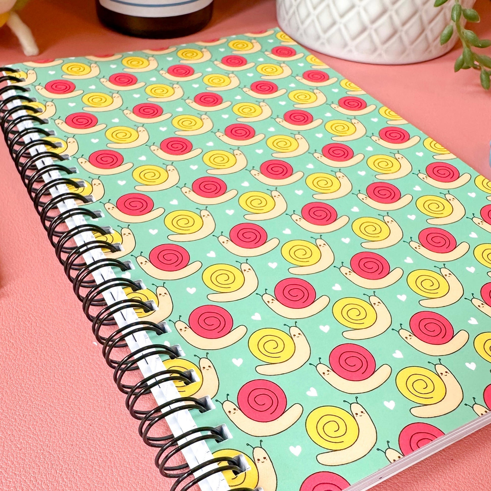 Notebook with snail pattern on a pink surface