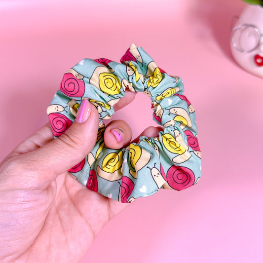 Hand holding a colorful scrunchie with a pink background