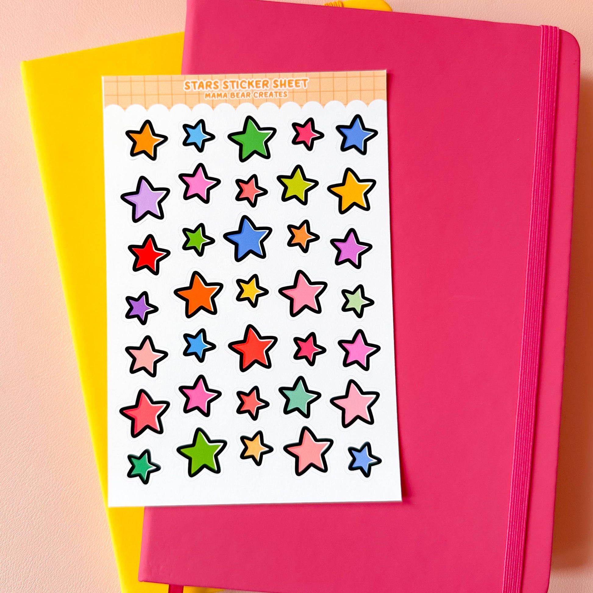 Colorful star sticker sheet on a pink notebook with a yellow cover.