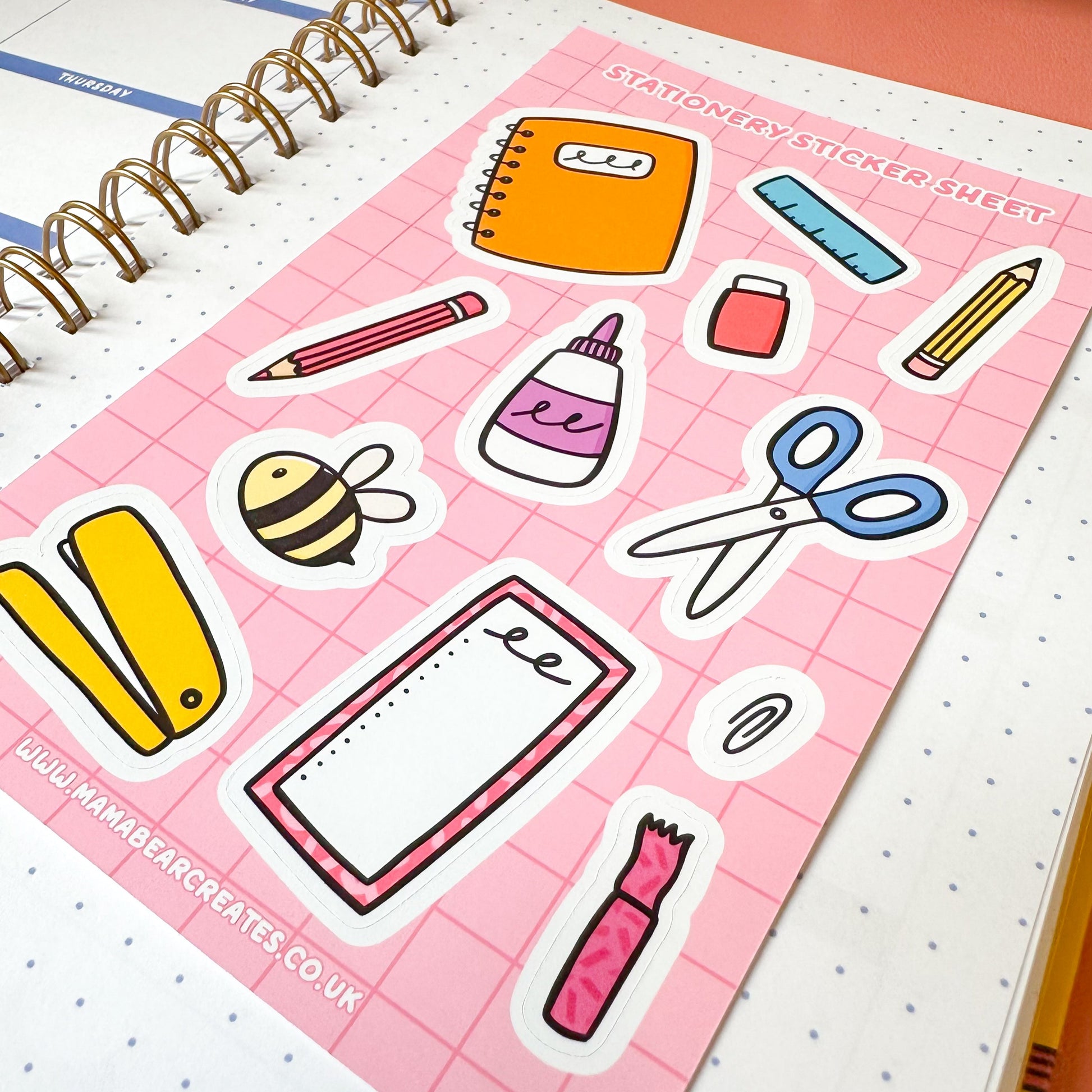 Sticker sheet with stationery-themed stickers on a pink grid background