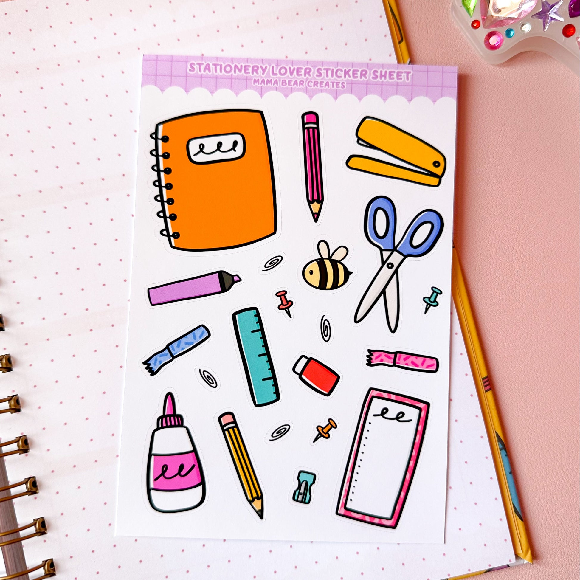 Stationery-themed sticker sheet on a pink surface with stationery items around