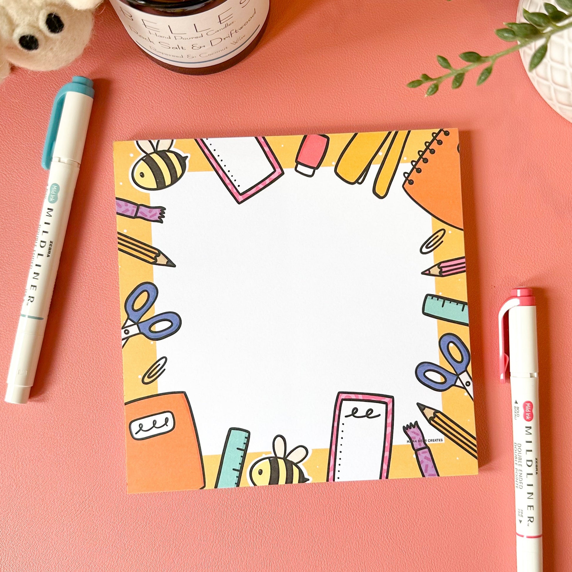 Colorful stationery-themed card on a pink surface with markers and a candle.