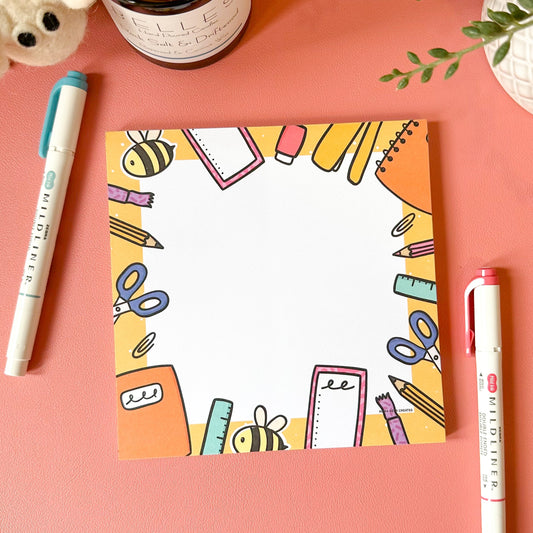 Colorful stationery-themed card on a pink surface with markers and a candle.