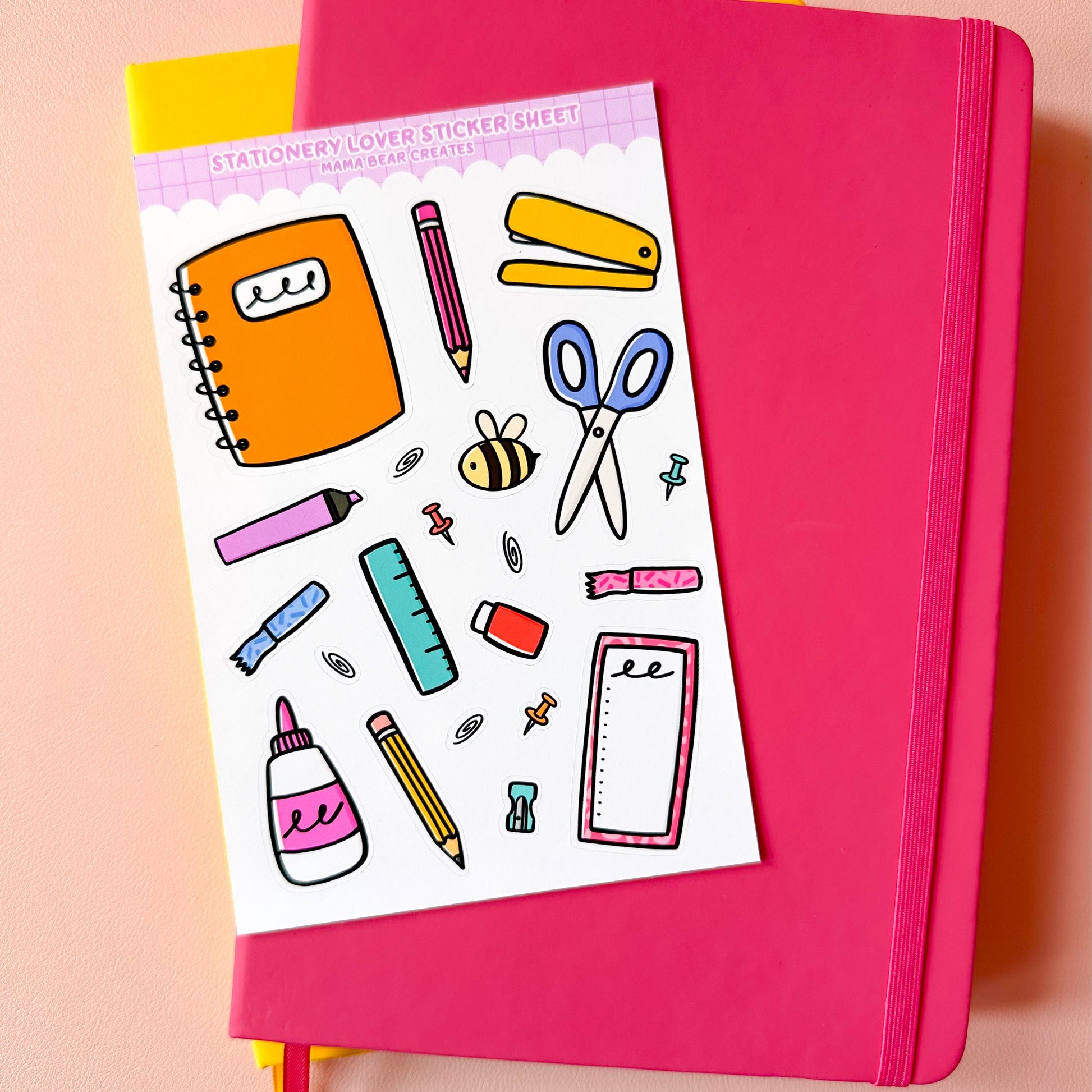 Pink notebook with stationery-themed sticker sheet on a peach background