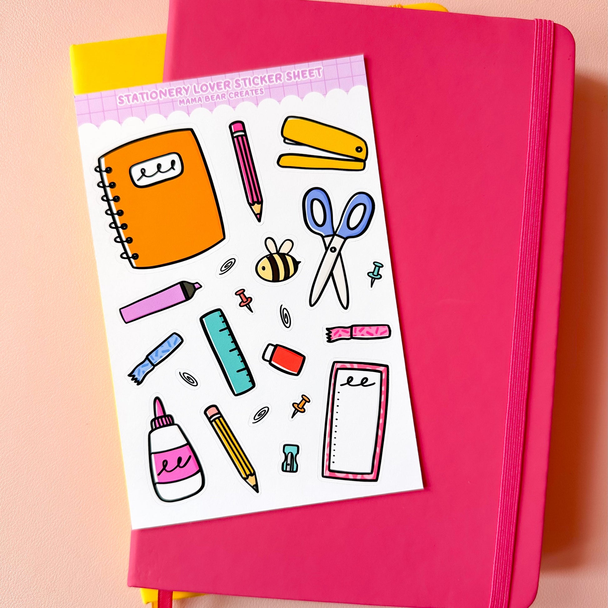 Pink notebook with stationery-themed sticker sheet on a peach background