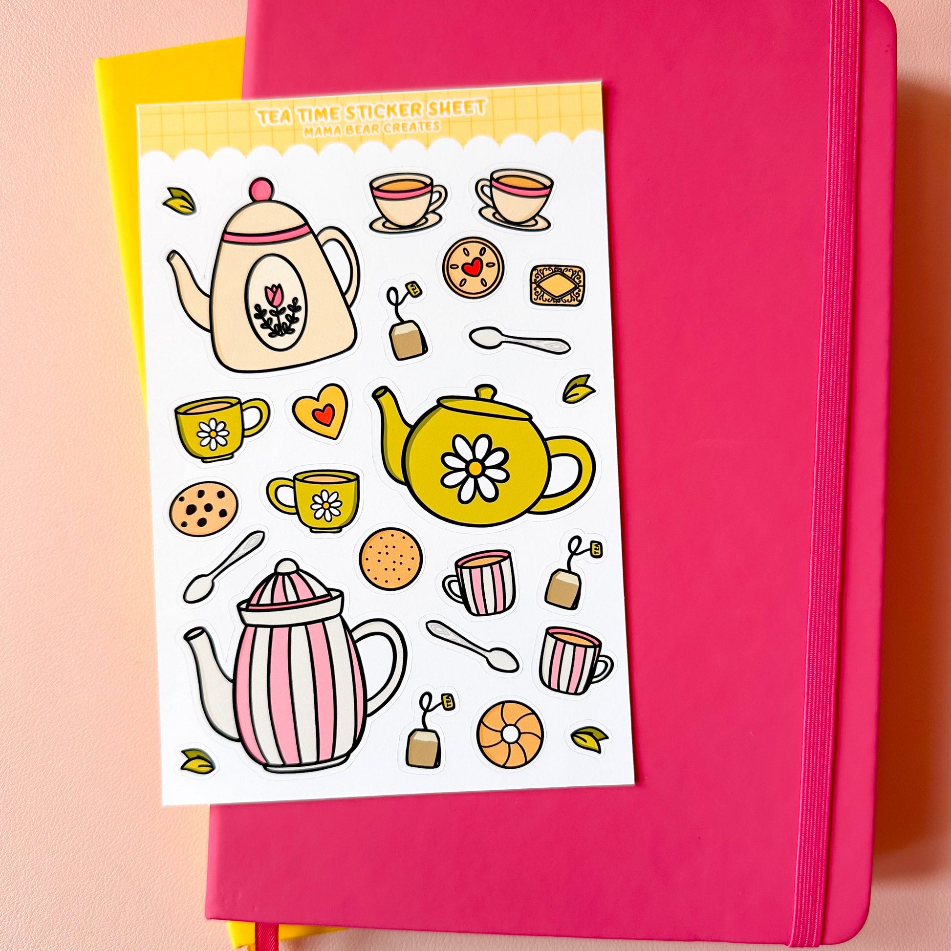 Pink notebook with a tea-themed sticker sheet on top against a pink background