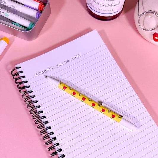 Notebook with a pen on a pink surface
