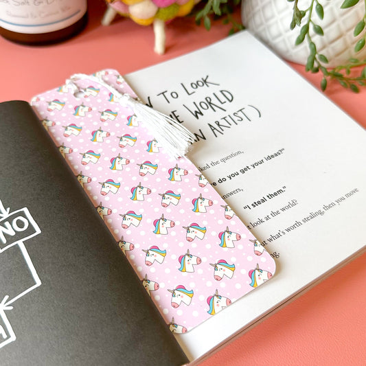 Pink bookmark with unicorn pattern on a book with text on a pink surface